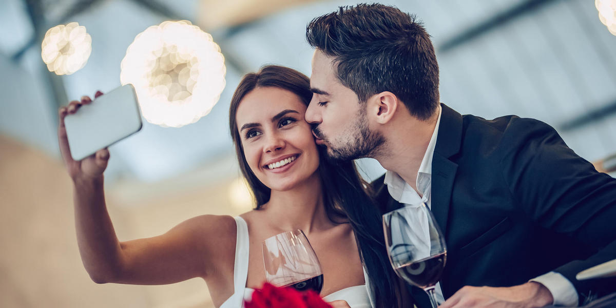 couple taking selfie with wine and roses